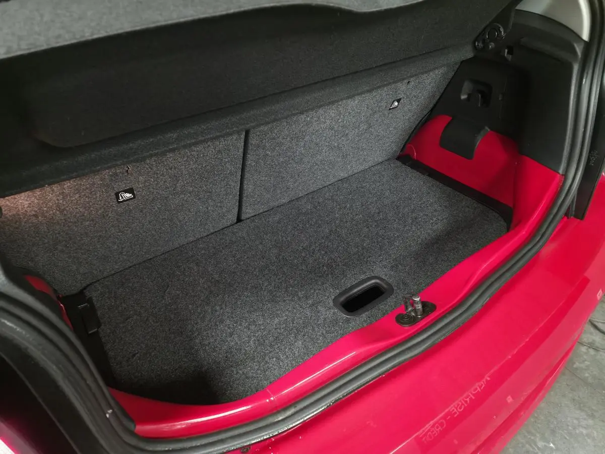 Coffre ouvert vu de dessus d'une Volkswagen Up rouge de 2018 avec habillage gris et rouge visible sur les côtés.