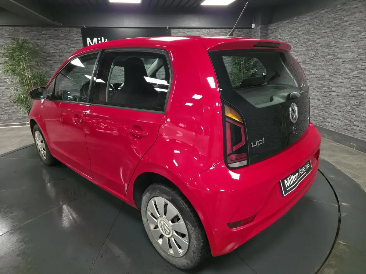 Volkswagen Up rouge vue 3/4 arrière droit, avec jantes acier et logo VW sur enjoliveurs spécifiques.