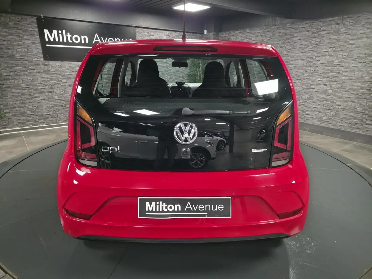 Vue arrière d'une Volkswagen Up rouge 2018 avec vitre arrière noire et logo VW centré.