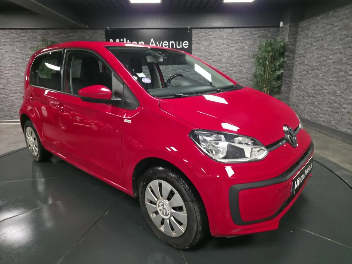 Vue 3/4 avant droit d'une Volkswagen Up rouge avec jantes acier et enjoliveurs spécifiques VW en aluminium.