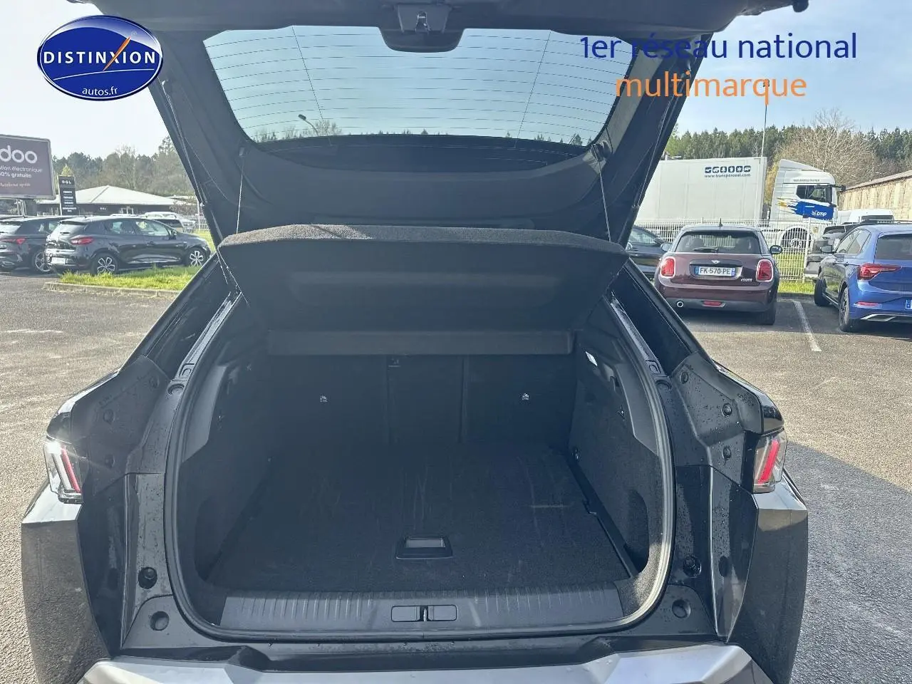 Coffre ouvert vue arrière d’un Peugeot 3008 noir perla nera meta 2024 sur parking extérieur.