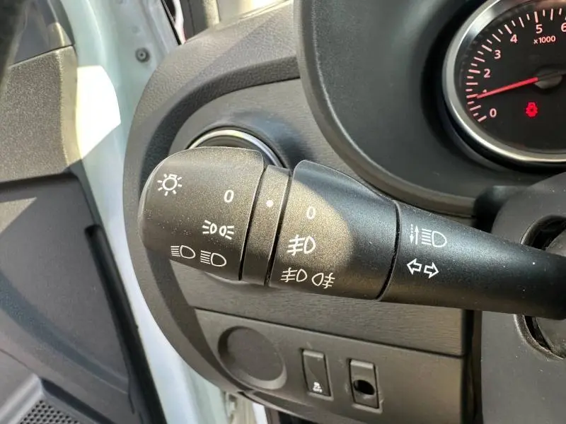 Gros plan sur la commande des feux et clignotants du tableau de bord d’un Dacia Lodgy blanc glacier 2022.
