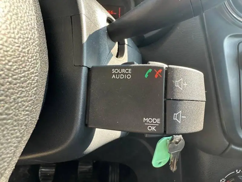 Détail de la commande audio au volant du Dacia Lodgy 2022, boutons pour source, mode et volume, intérieur noir.