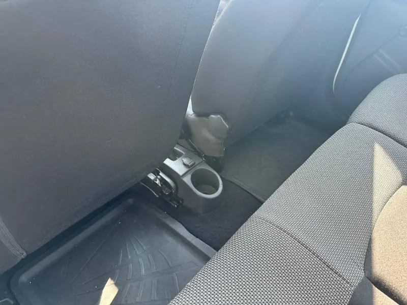 Vue intérieure arrière montrant le plancher et porte-gobelet entre les sièges avant d'une Dacia Lodgy blanc glacier 2022.