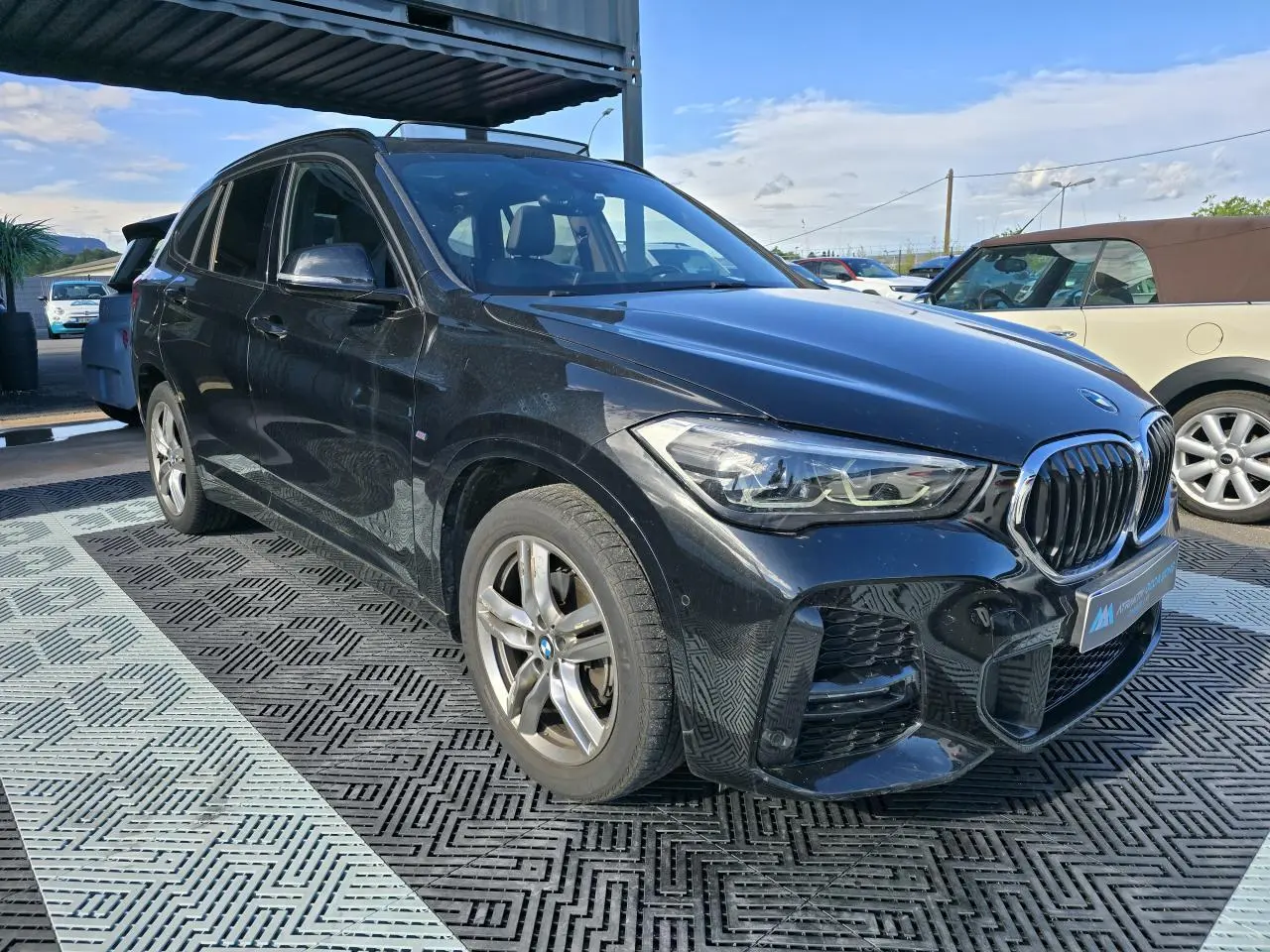 BMW X1 noir saphir métal vue 3/4 avant droit avec calandre Shadow Line et jantes 18 pouces M Sport.