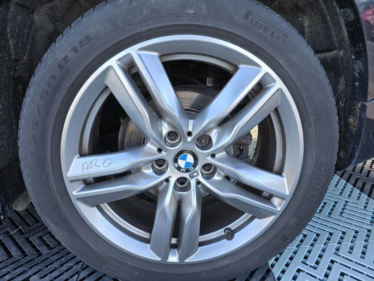 Gros plan sur la jante alliage 18 pouces bicolore M Sport d'un BMW X1 noir Saphir Metal, avec logo BMW central.