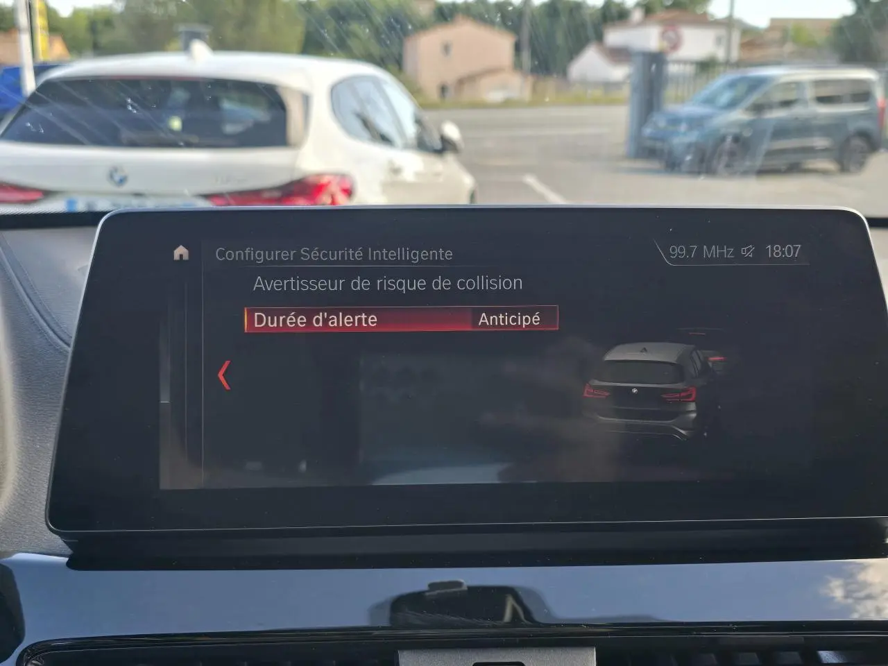 Affichage tête haute montrant un BMW X1 noir saphir métal vu de l'arrière sur l'écran multimédia intérieur.