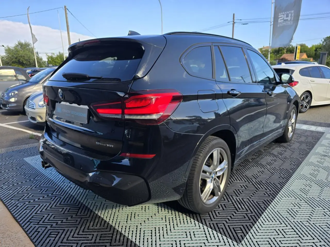 Vue 3/4 arrière droite d'un BMW X1 noir saphir métallisé avec feux arrière LED et jantes alliage 18 pouces.