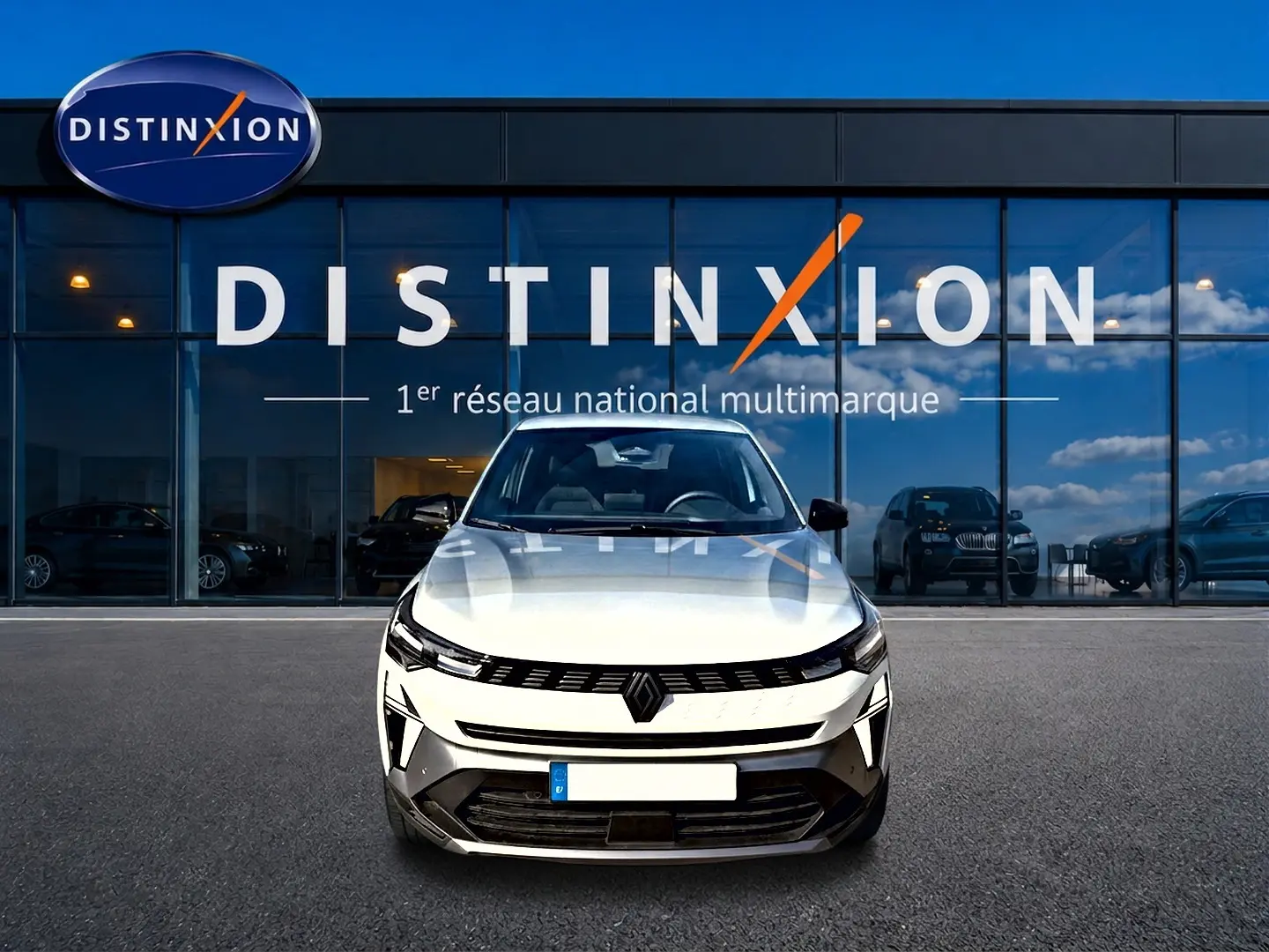 Vue avant d'une Renault Symbioz blanc nacré garée devant une vitrine avec logo Distinxion.
