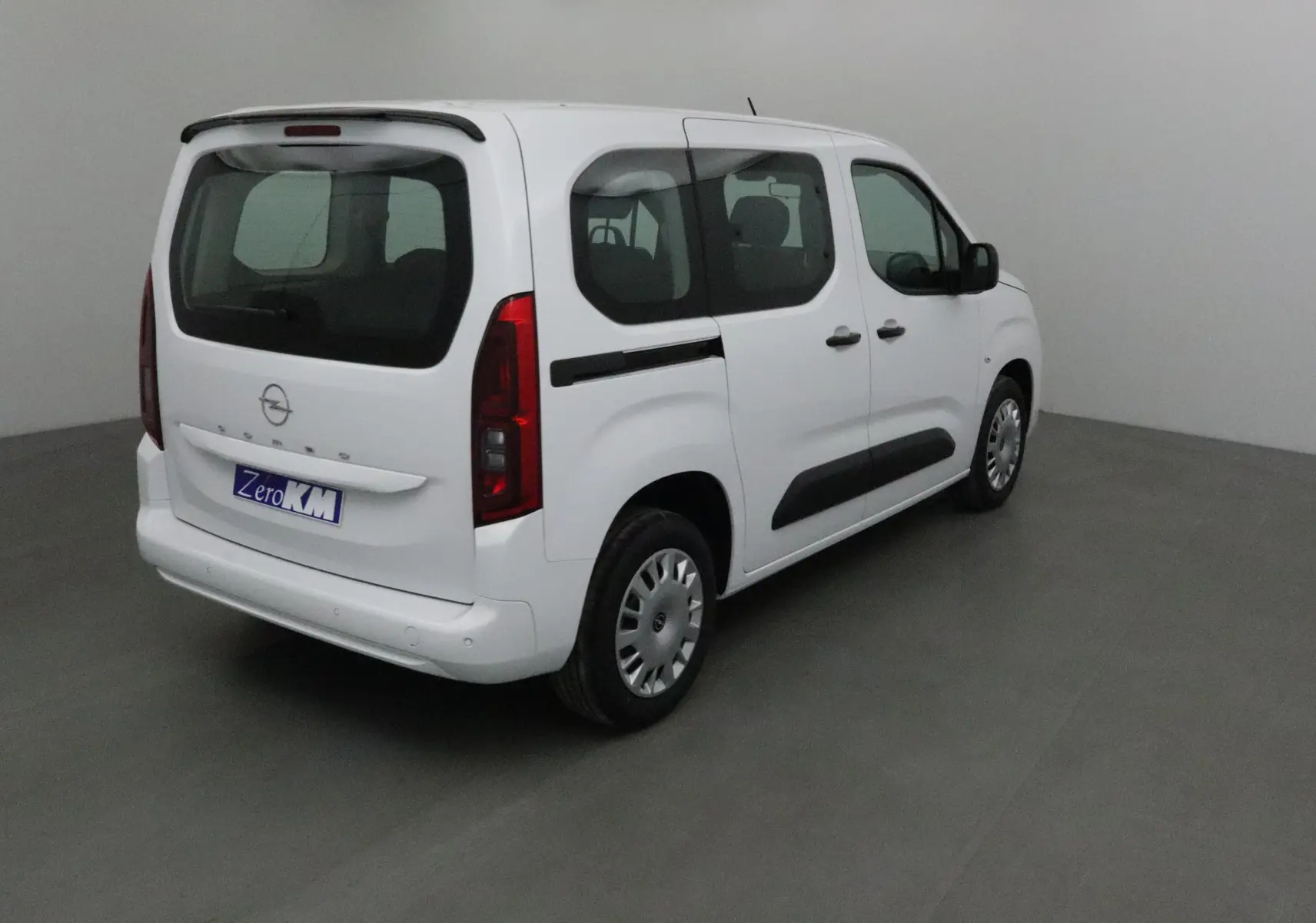 Opel Combo Life blanc en 3/4 arrière droit, avec becquet et vitres teintées dans un studio neutre.