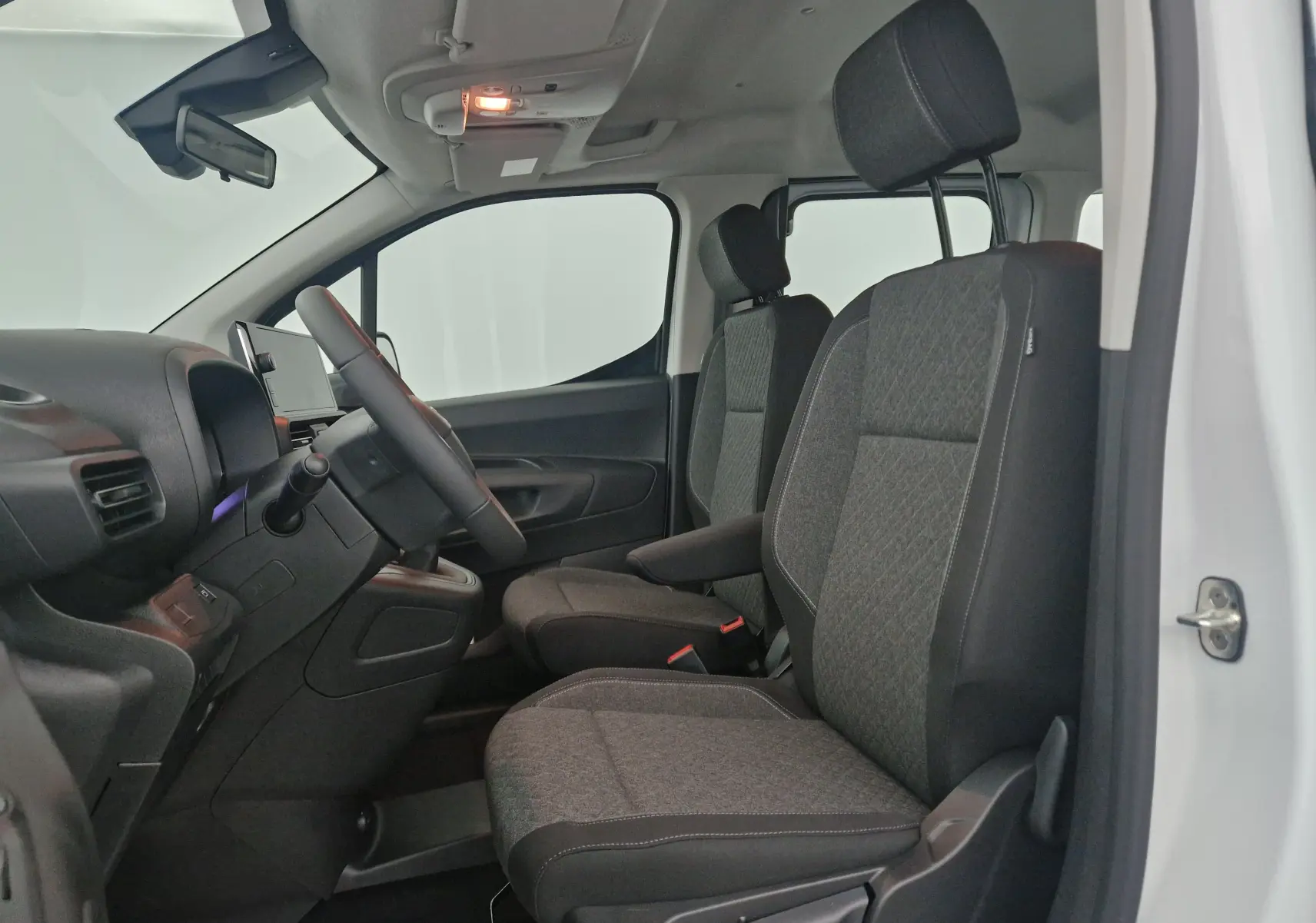 Intérieur avant côté gauche d’un Opel Combo Life blanc, montrant les sièges tissu gris et le tableau de bord épuré.