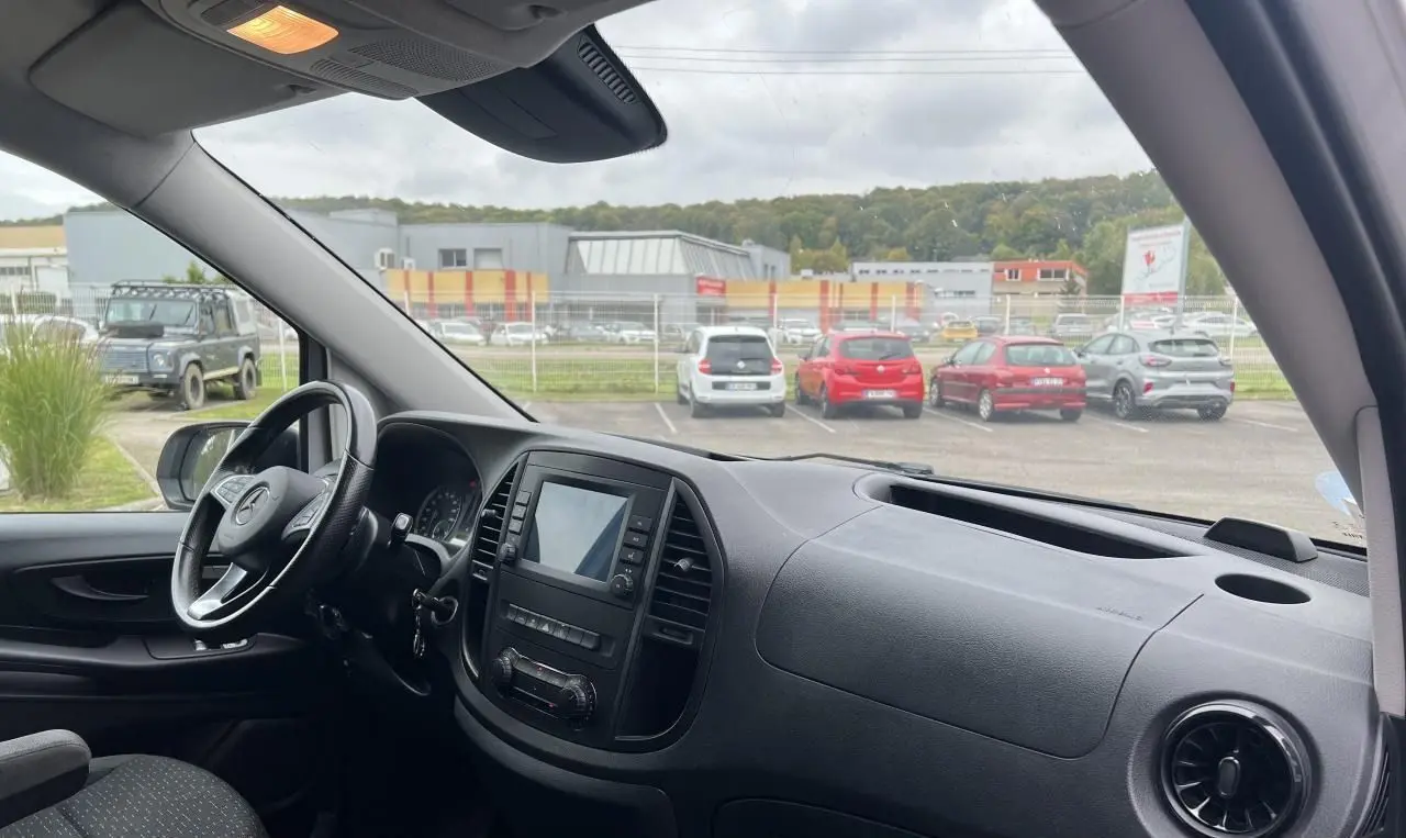 Vue intérieure côté conducteur du Mercedes Vito Fourgon blanc, mettant en valeur le tableau de bord avec écran tactile et volant multifonction.