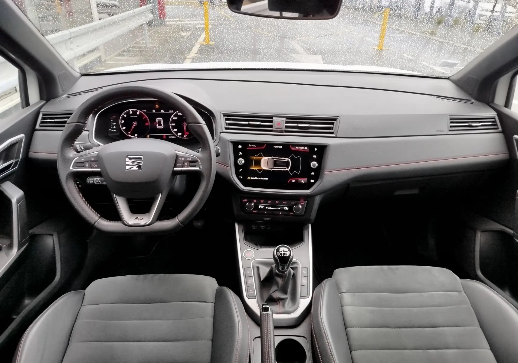Vue intérieure avant du SEAT Arona 2020, tableau de bord noir avec volant multifonction et boîte manuelle.
