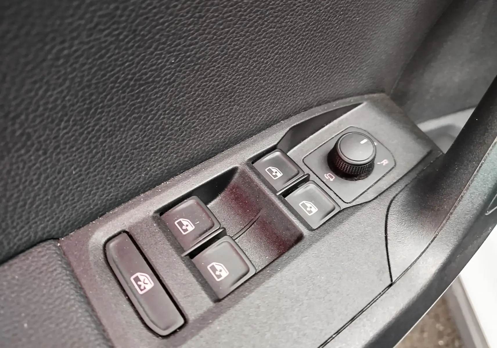 Gros plan sur les commandes de lève-vitres et réglage des rétroviseurs côté conducteur du SEAT Arona blanc toit gris.