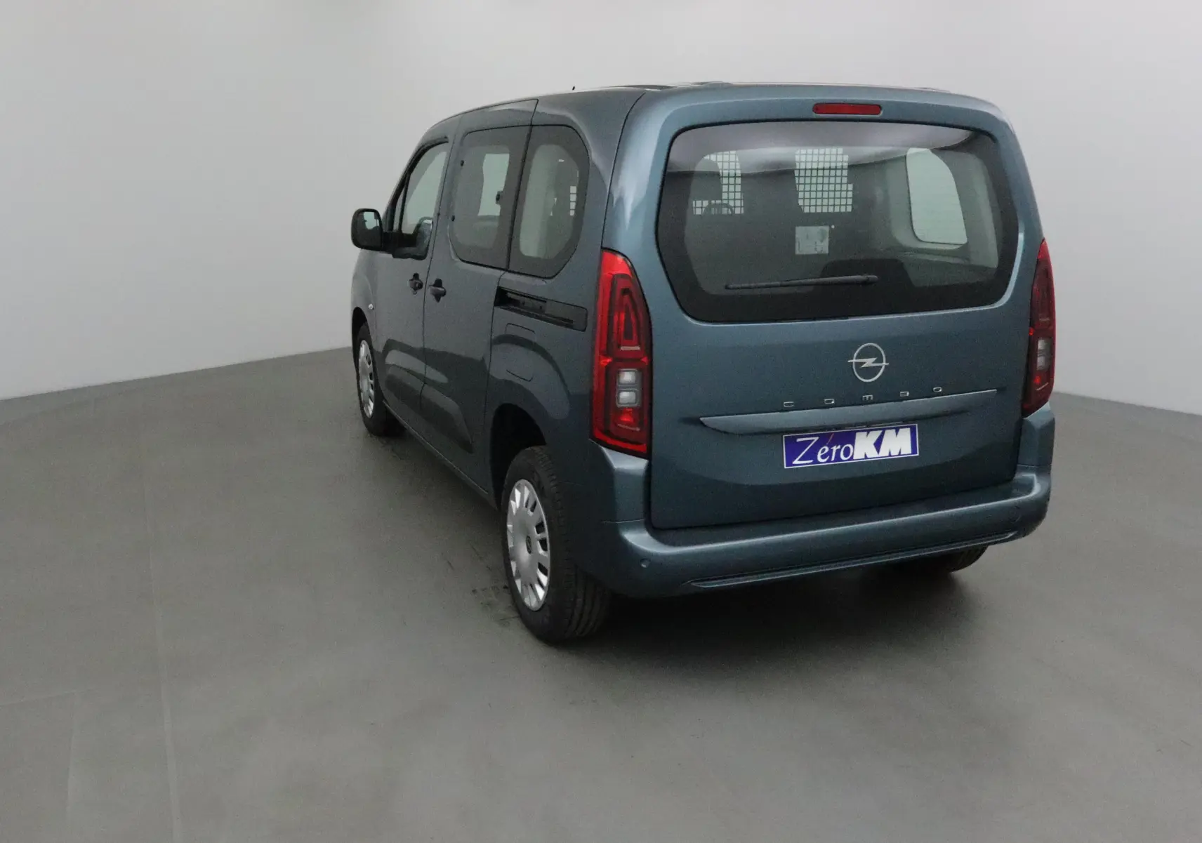 Vue 3/4 arrière gauche d'un Opel Combo Life bleu Kiama avec grille de séparation visible à l'intérieur.