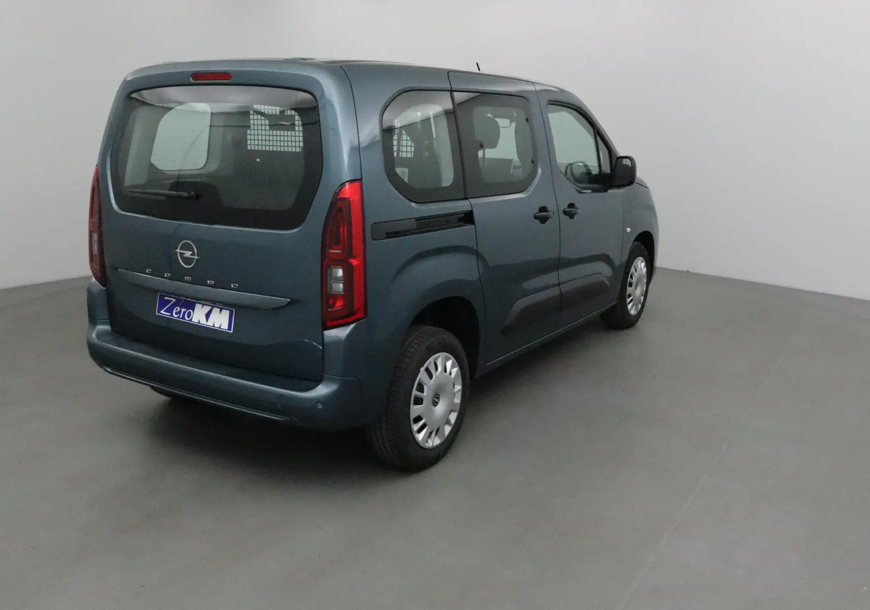 Vue 3/4 arrière droite d'un Opel Combo Life bleu Kiama avec grille de séparation visible à l'intérieur.