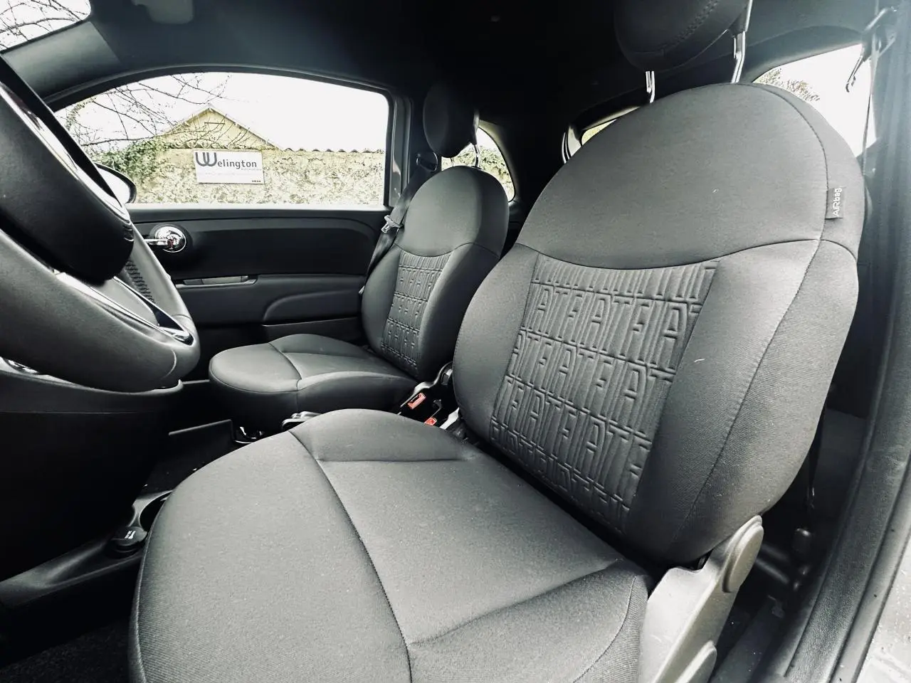 Vue intérieure côté droit des sièges avant gris foncé avec motif Fiat embossé sur une Fiat 500 2023.