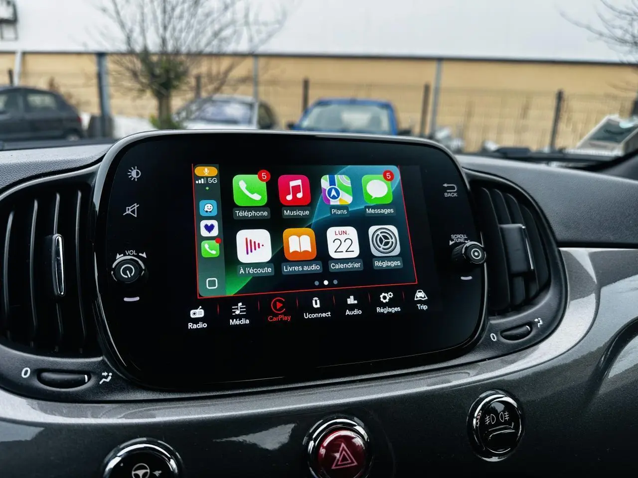 Écran tactile central de la Fiat 500 2023 gris foncé avec interface Apple CarPlay affichée, vue intérieure frontale.