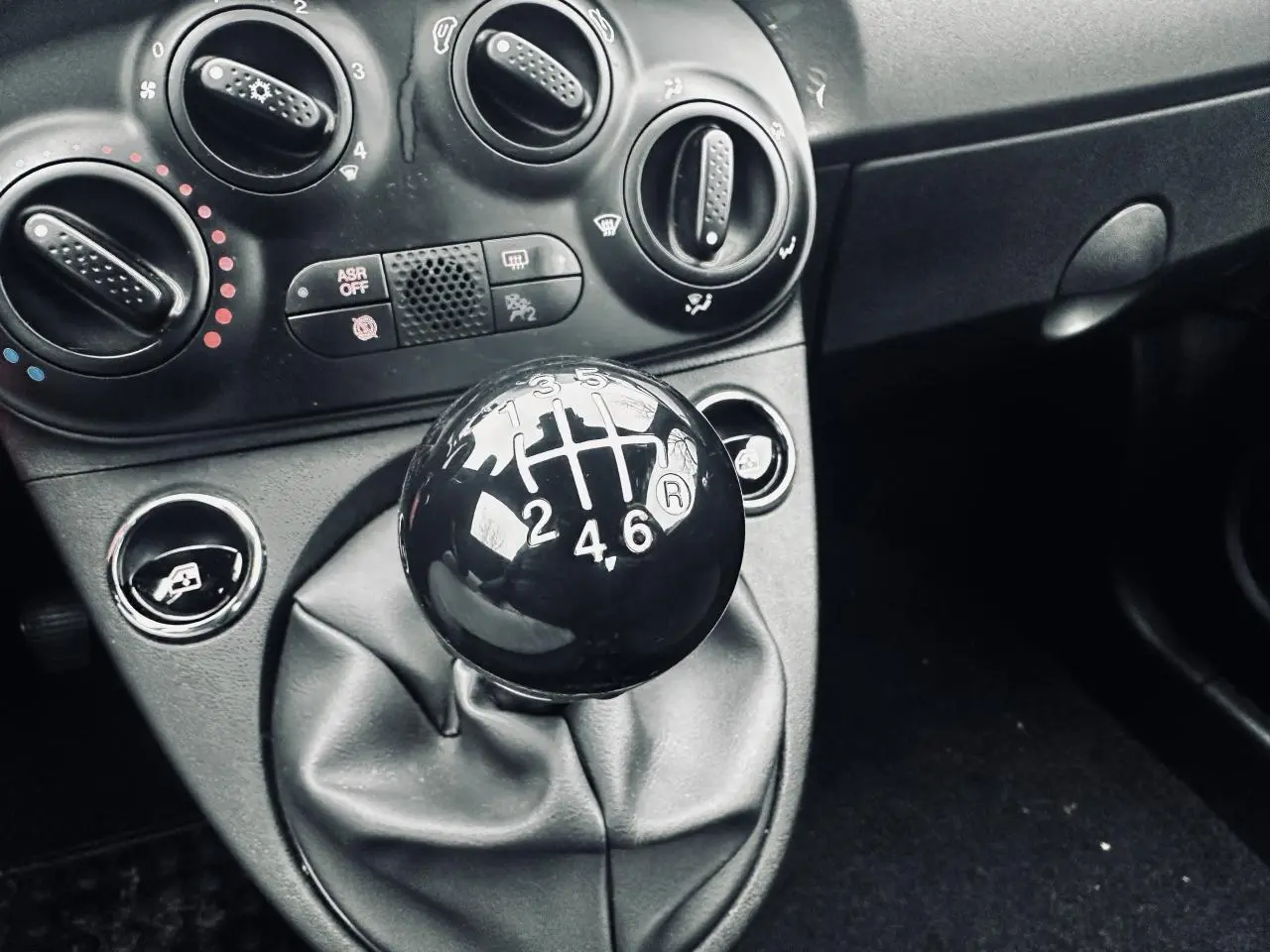 Gros plan sur le levier de vitesses manuel noir et la console centrale grise de la Fiat 500 gris foncé 2023.