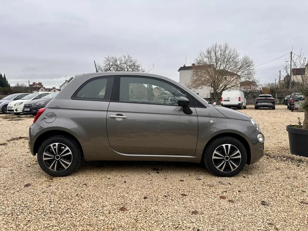 Profil côté gauche de la Fiat 500 gris foncé 2023 avec jantes alliage 15 pouces et rétroviseurs noirs grainés.