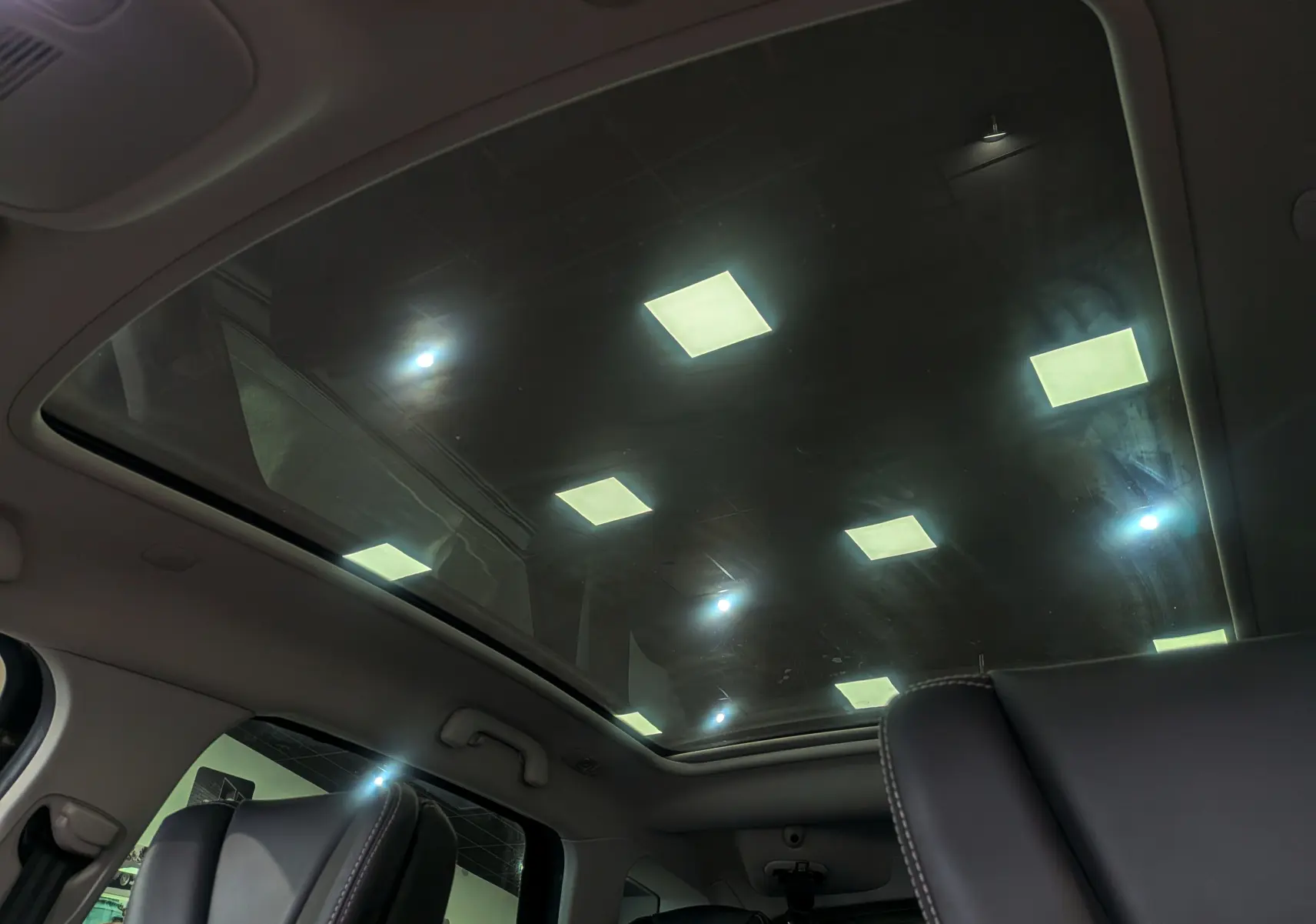 Toit panoramique en verre vu de l'intérieur arrière du Renault Scenic IV Initiale Paris, avec sièges cuir noir visibles.