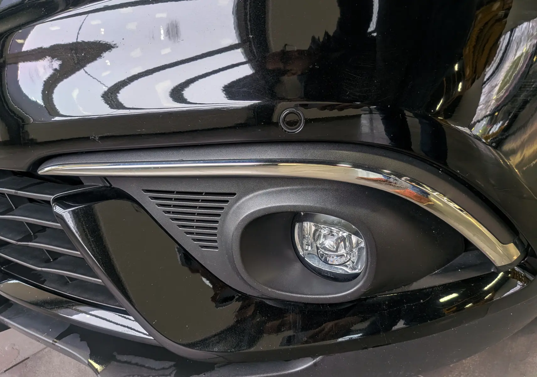 Gros plan sur le feu antibrouillard avant droit noir étoilé de la Renault Scénic IV dCi 160 Energy EDC Initiale Paris.