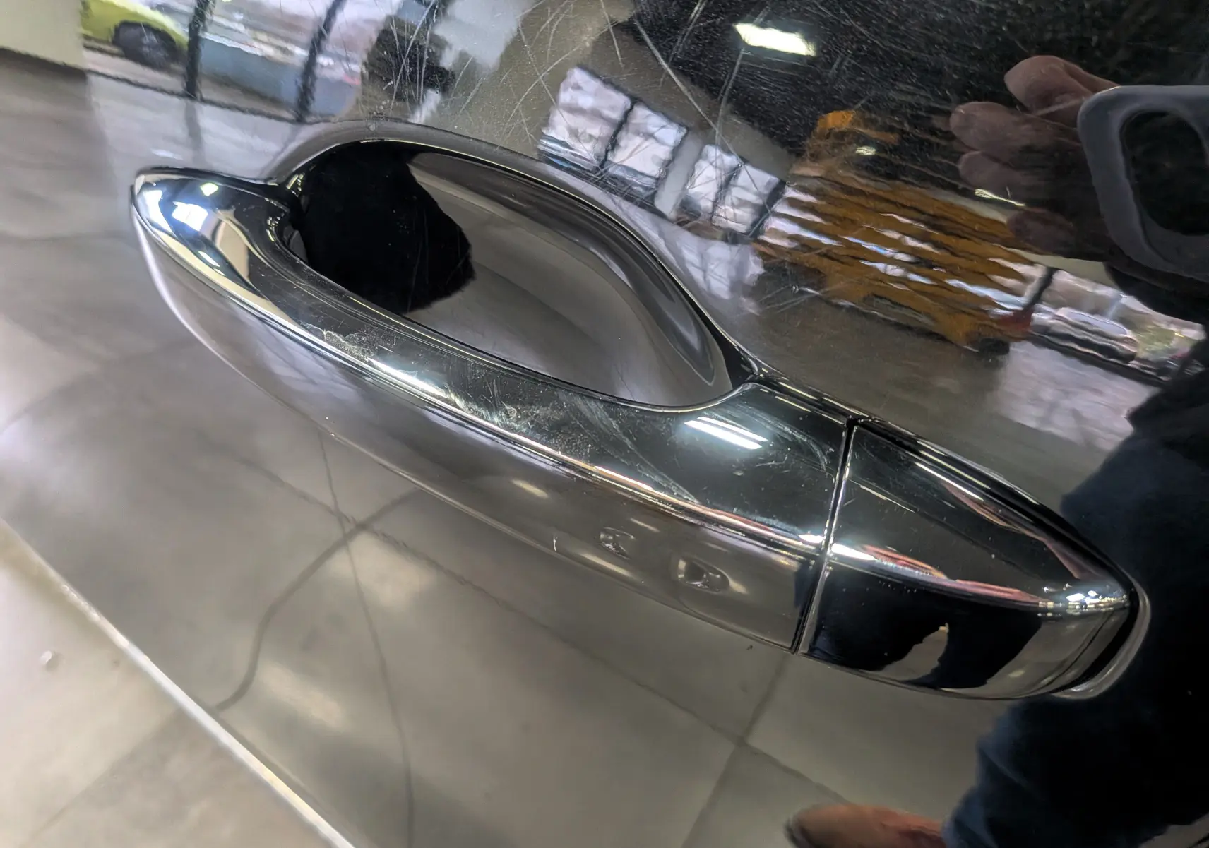 Poignée de porte chromée en gros plan sur la porte côté gauche d’une Renault Scénic IV noir étoilé.