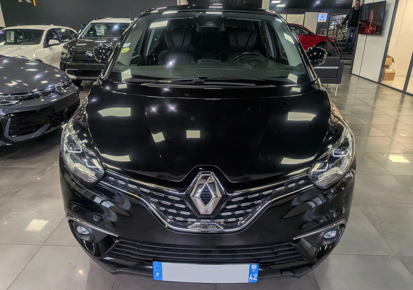 Vue de face d'un Renault Scénic IV noir étoilé, mettant en valeur sa calandre chromée et ses phares LED.