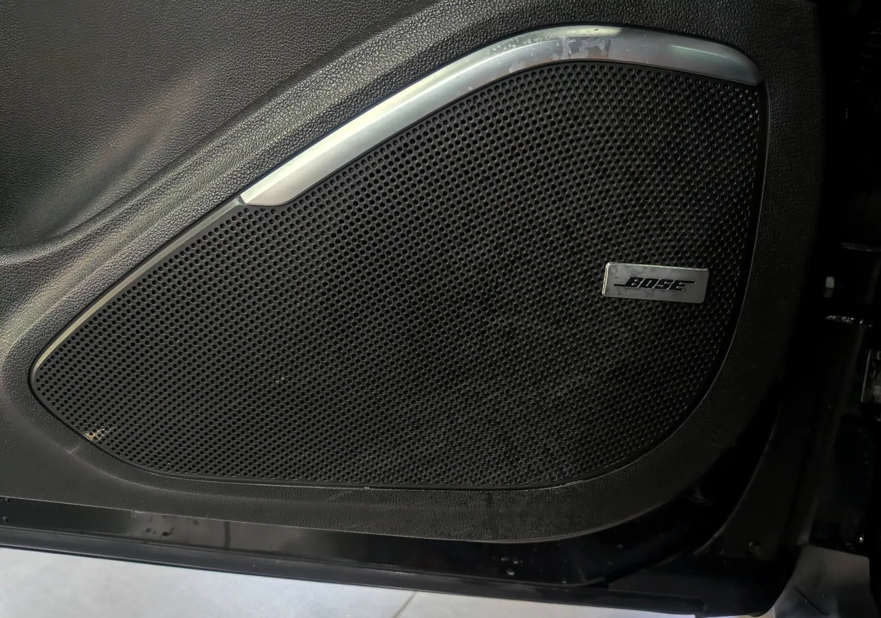 Gros plan sur l'enceinte Bose intégrée à la porte côté gauche d'un Renault Scenic IV noir étoilé.