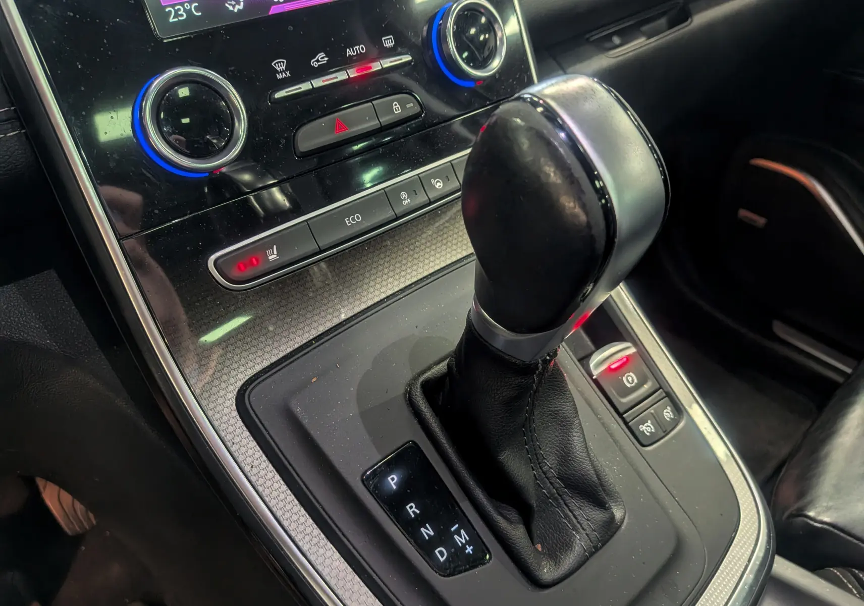 Gros plan sur la console centrale du Renault Scénic IV noir étoilé, montrant le levier de vitesse automatique et les commandes de climatisation.