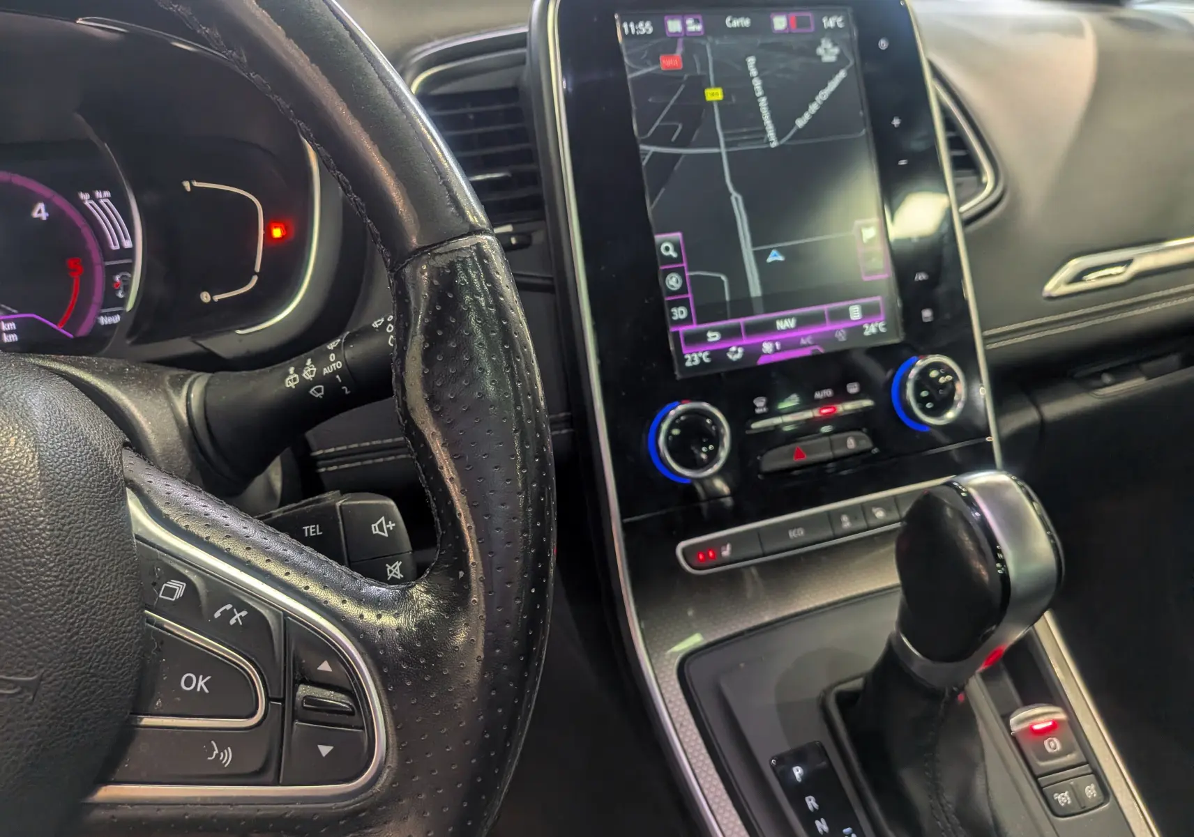 Vue intérieure rapprochée du tableau de bord et levier de vitesse d’une Renault Scenic IV noir étoilé avec écran tactile de navigation.