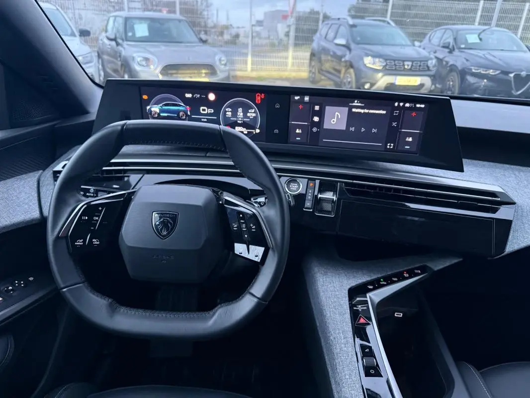Vue intérieure frontale du cockpit numérique du Peugeot 3008 Hybrid 145 Allure bleu, volant compact et tableau de bord moderne.