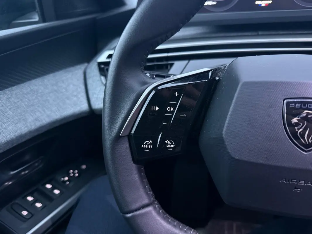 Gros plan sur le volant noir du Peugeot 3008 Hybrid 145 Allure 2025 avec commandes intégrées côté gauche.