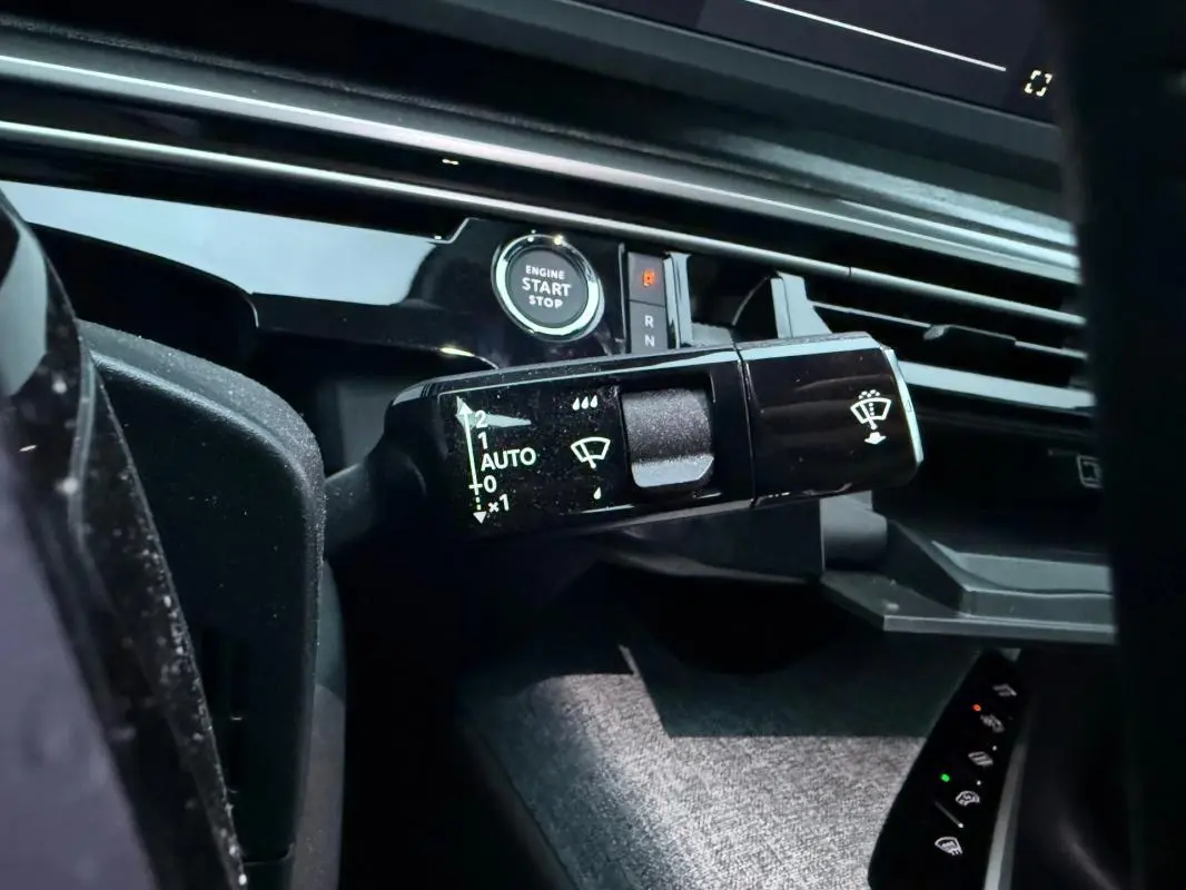 Gros plan sur la commande d’essuie-glace et le bouton start/stop du tableau de bord du Peugeot 3008 Hybrid bleu.