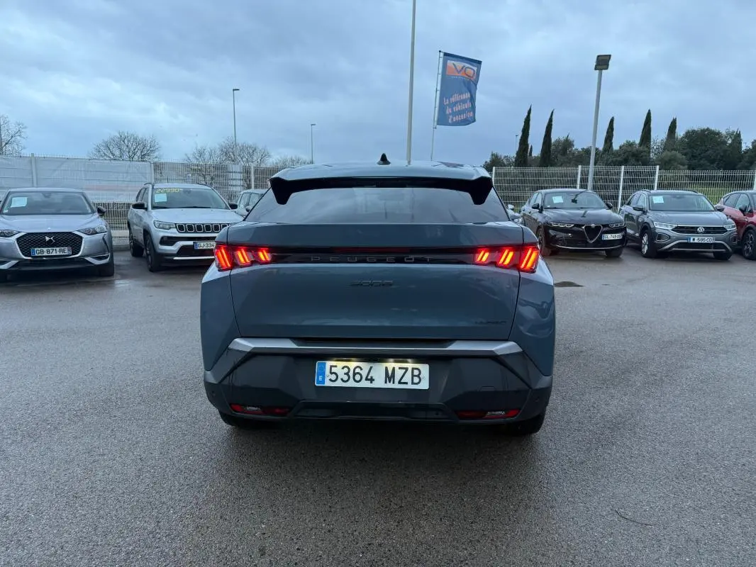 Vue arrière d’un Peugeot 3008 Hybrid bleu 2025 avec feux allumés et jantes alliage 19 pouces sur parking.