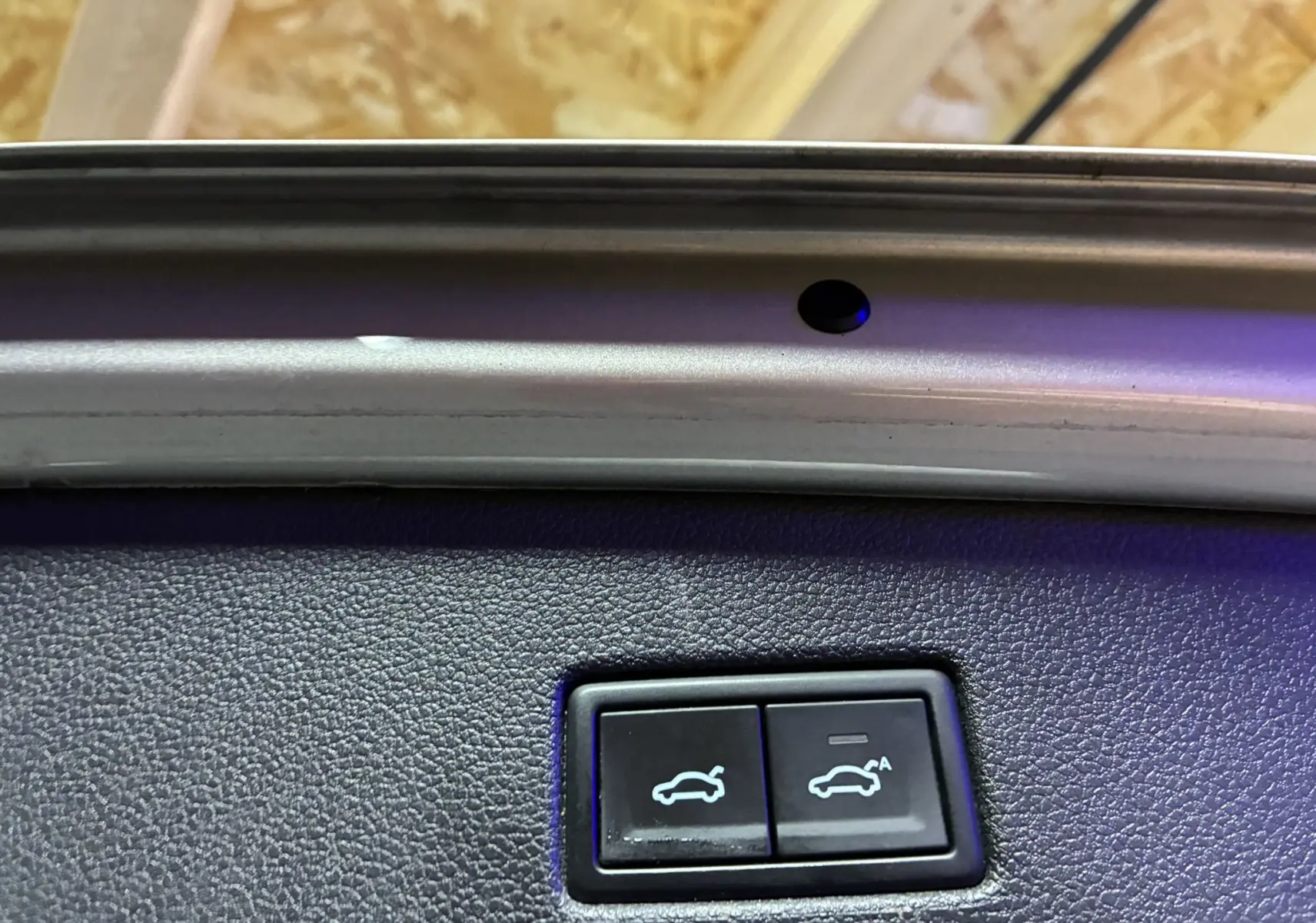 Gros plan sur les boutons d'ouverture et fermeture électrique du hayon intérieur d'un Volkswagen Tiguan gris.