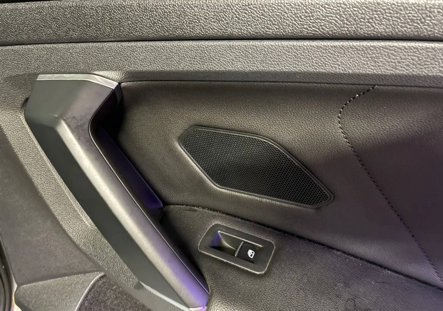 Détail de la portière intérieure côté gauche du Volkswagen Tiguan 2.0 TDI 150 Carat 2017 avec bouton de commande de vitre et haut-parleur intégré.