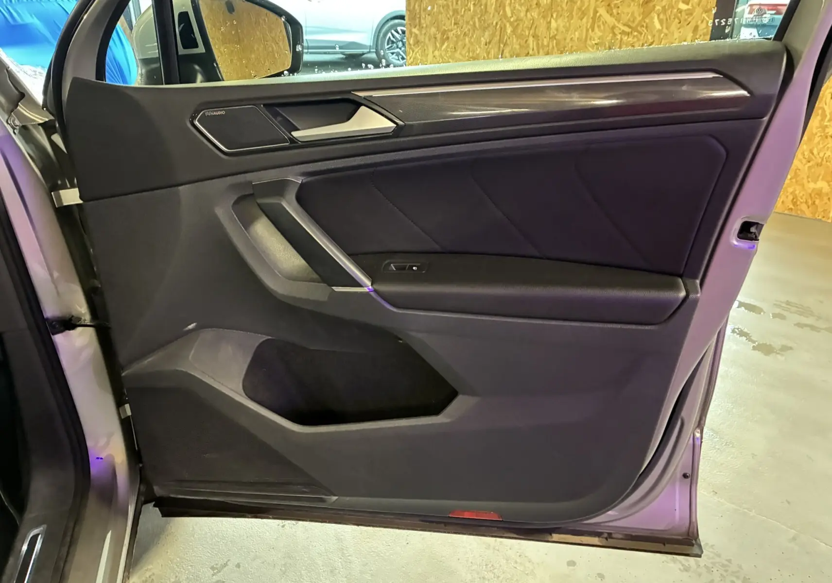 Vue intérieure de la porte avant gauche du Volkswagen Tiguan gris, avec habillage noir et haut-parleur intégré.
