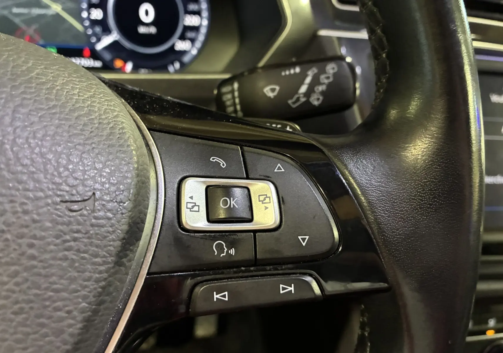 Gros plan sur les commandes multifonctions à droite du volant noir du Volkswagen Tiguan 2.0 TDI 150 Carat 2017.