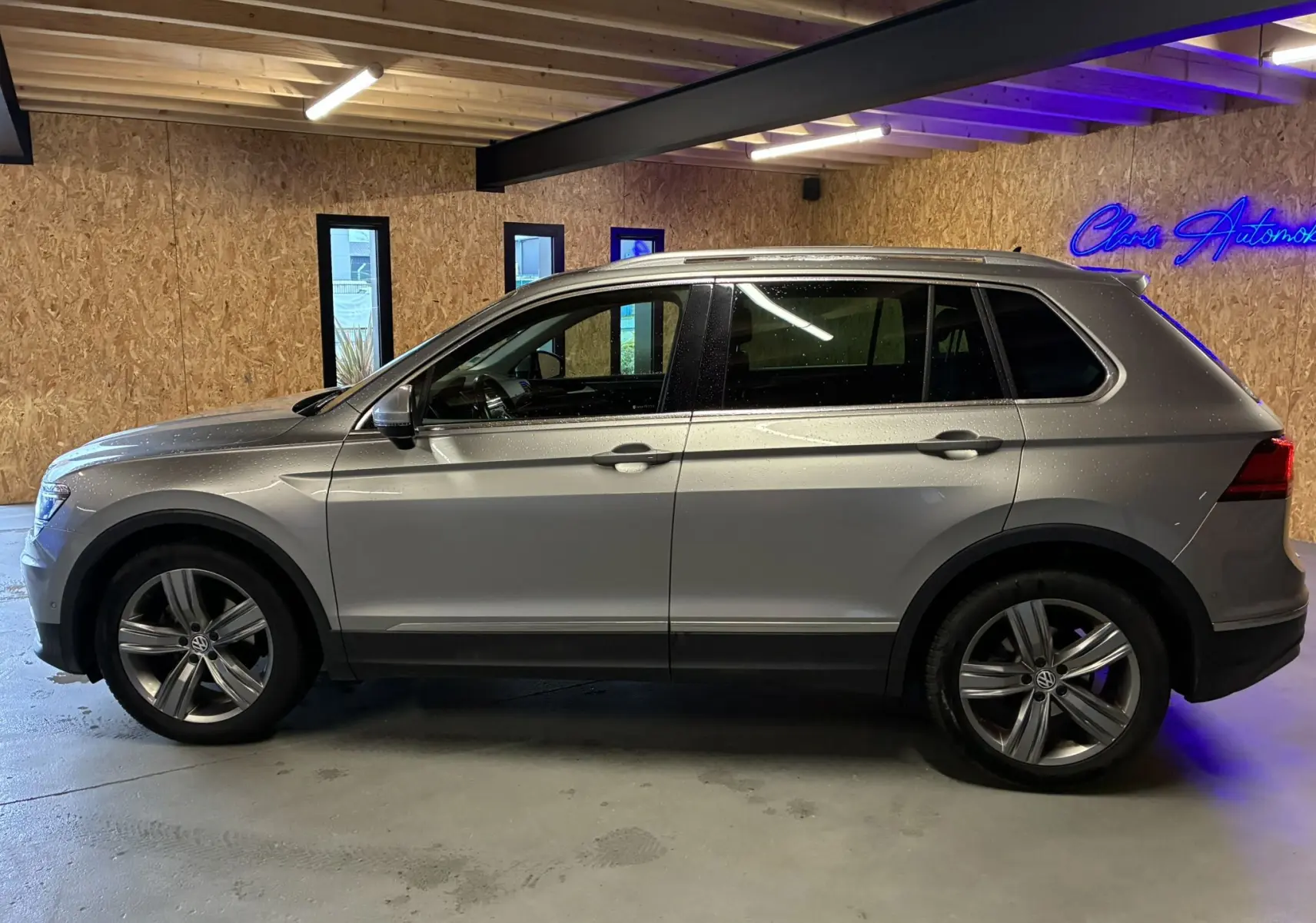Vue de profil côté gauche d'un Volkswagen Tiguan 2.0 TDI 150 Carat gris, avec jantes alliage 19 pouces et intérieur cuir noir visible.