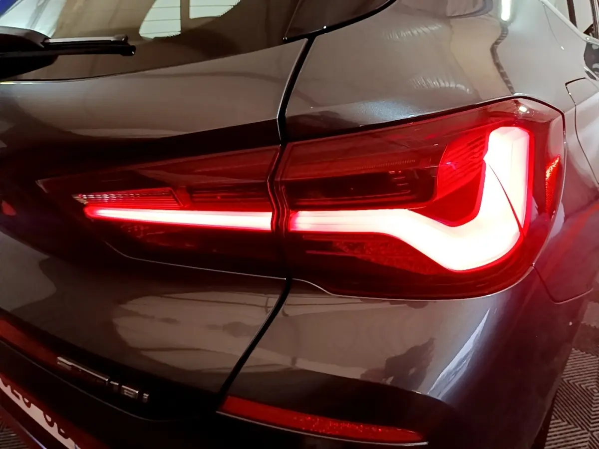 Gros plan sur le feu arrière droit allumé d'une BMW X2 sDrive18i Lounge gris foncé, soulignant les lignes modernes du véhicule.