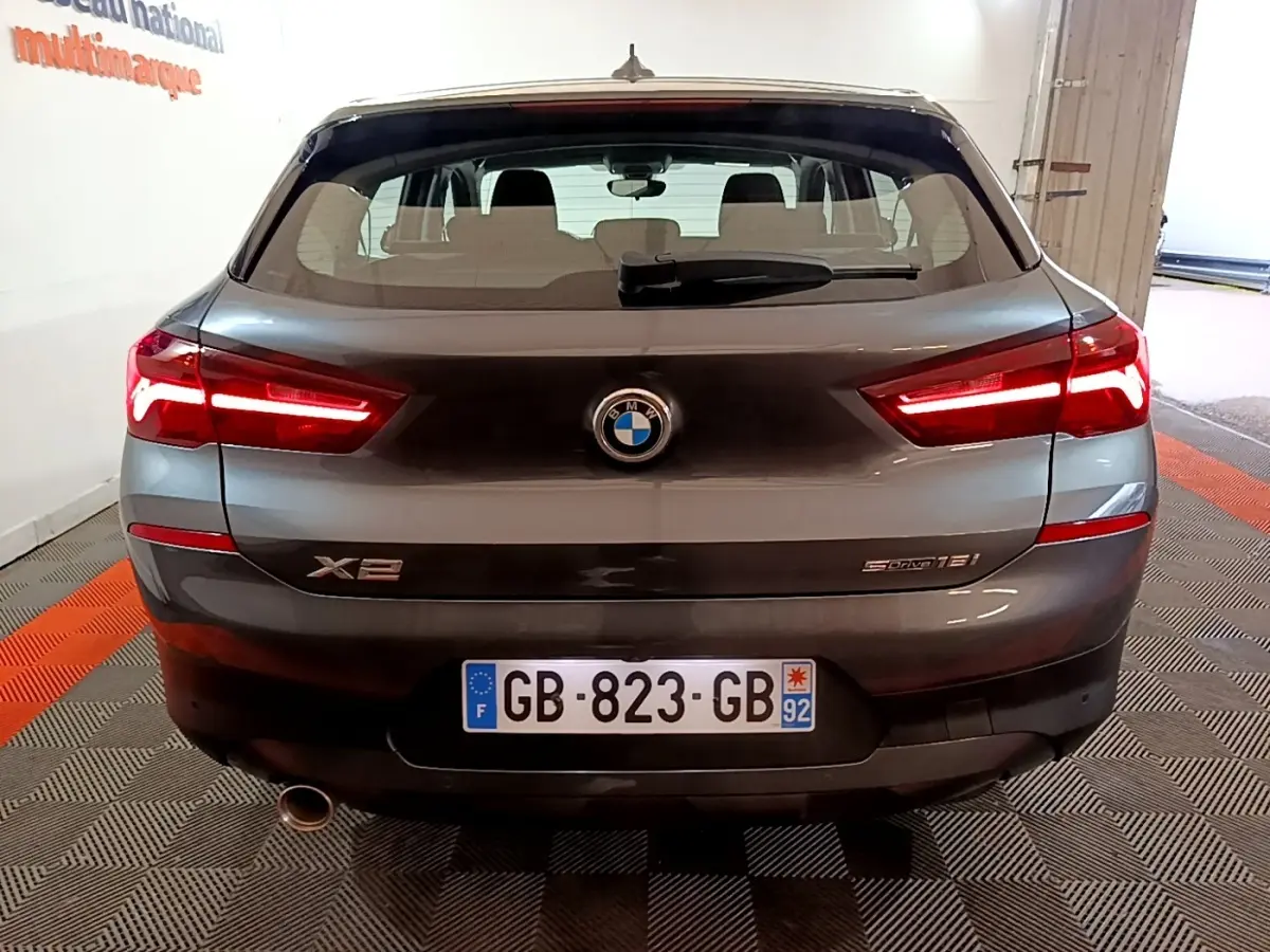 Vue arrière d’un BMW X2 sDrive18i gris foncé avec feux LED allumés et plaque d’immatriculation française visible.