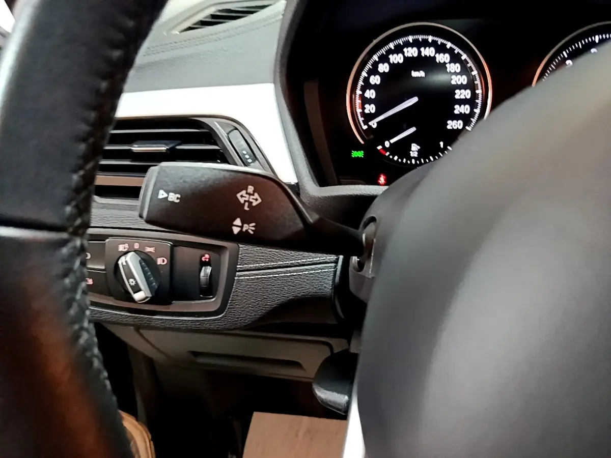 Gros plan sur le volant cuir et le combiné d'instruments lumineux du tableau de bord d'une BMW X2 2021 gris foncé.