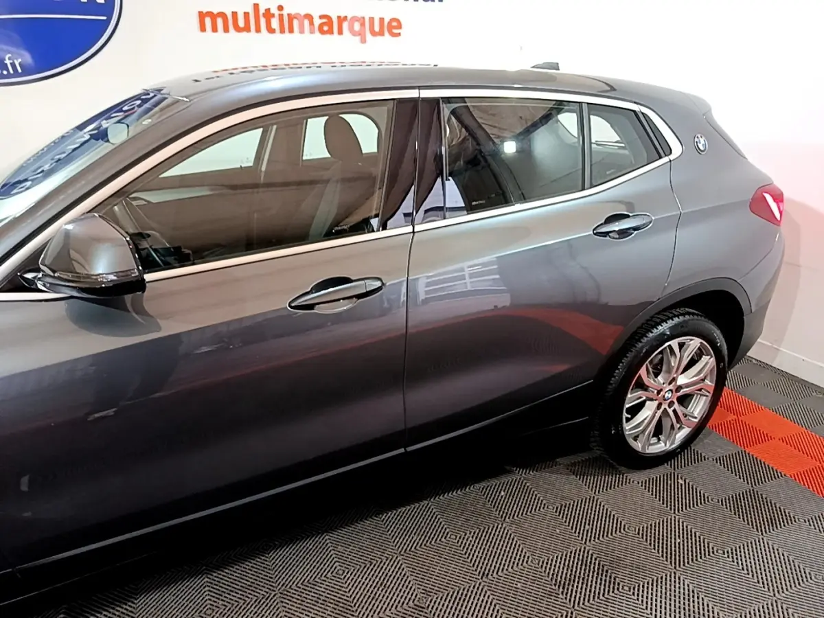 Vue latérale droite d'un BMW X2 gris foncé avec jantes alliage et rétroviseurs électriques rabattables.
