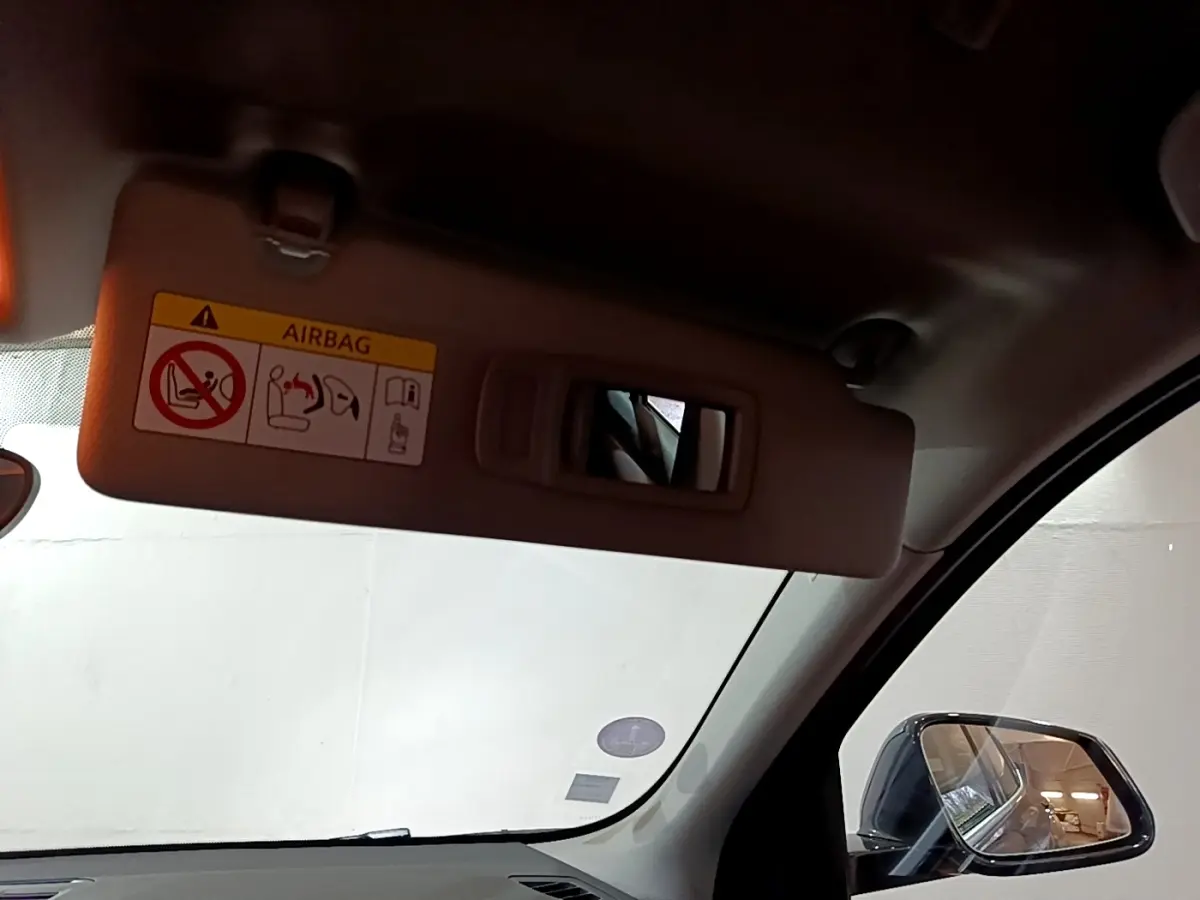 Détail du pare-soleil côté conducteur avec miroir intégré et rétroviseur extérieur noir d'une BMW X2 gris foncé.