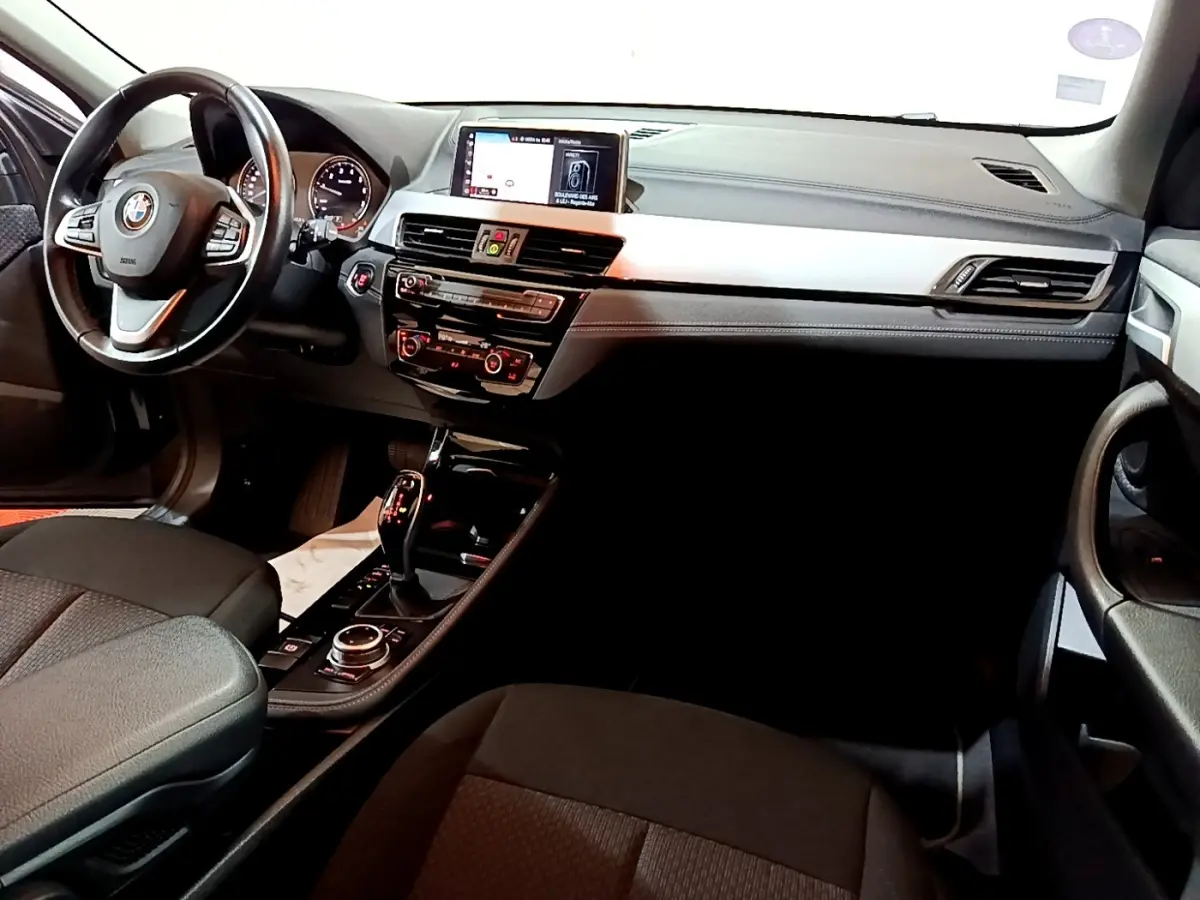 Vue intérieure de face droite du tableau de bord noir et gris avec écran central et volant cuir de la BMW X2 sDrive18i Lounge DKG7.