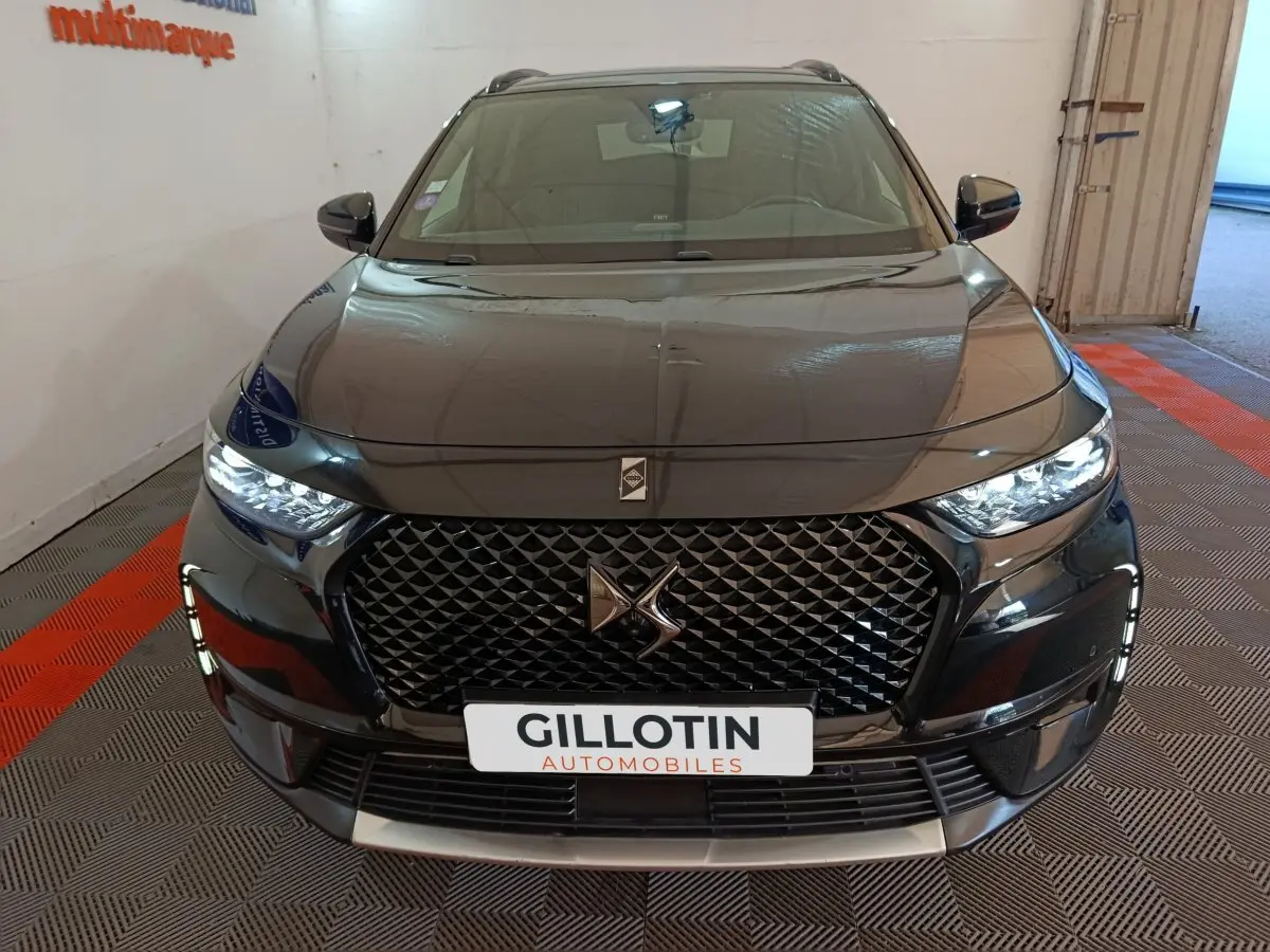 Vue avant du DS7 Crossback E-TENSE 4x4 300 noir brillant avec calandre distinctive et phares LED allumés.