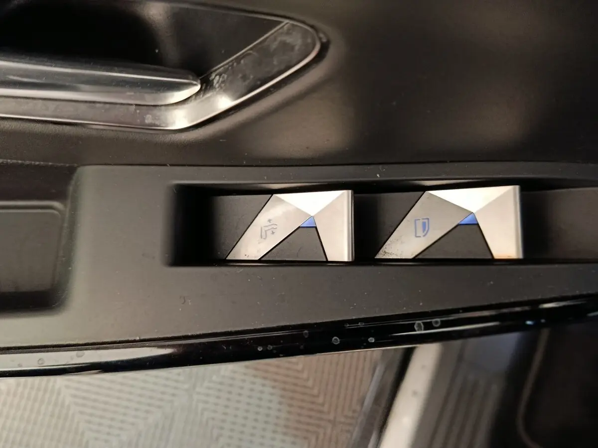 Gros plan sur les boutons de réglage des rétroviseurs argentés et noirs dans l'habitacle du DS7 Crossback noir.