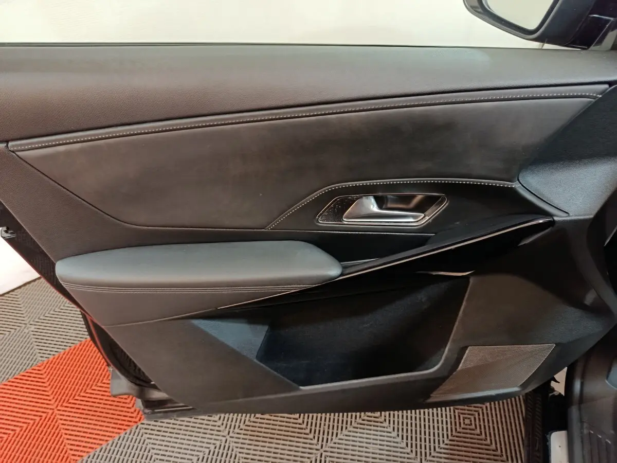 Gros plan sur la porte intérieure côté gauche du DS7 Crossback E-TENSE 4x4 300 Louvre noire, avec garniture cuir et poignée métal.