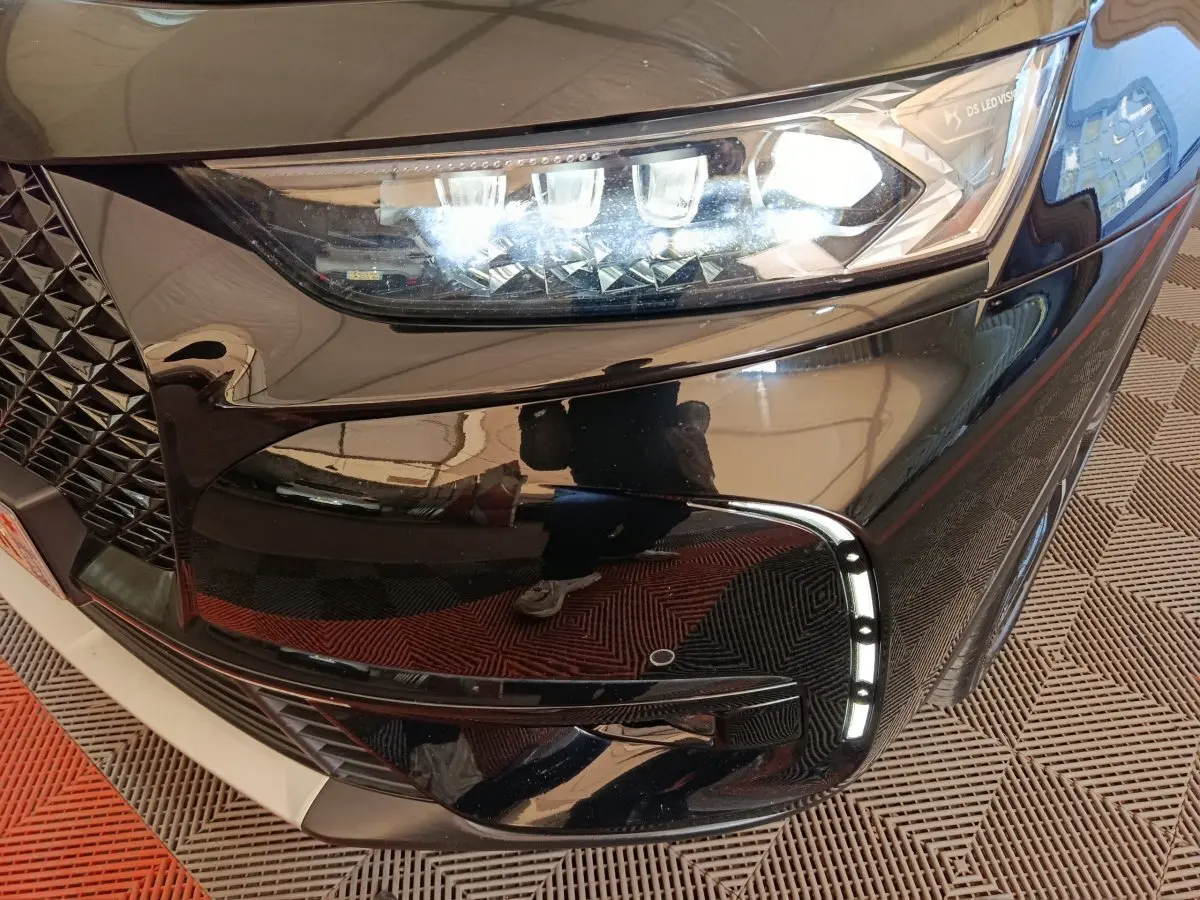 Gros plan sur le phare avant droit noir brillant du DS7 Crossback E-TENSE 4x4 300 LOUVRE avec feux LED et détails chromés.